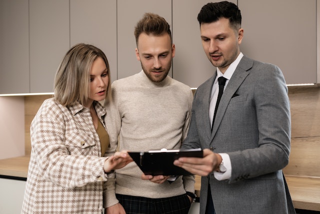 A property manager looking at a document on a clipboard with two people